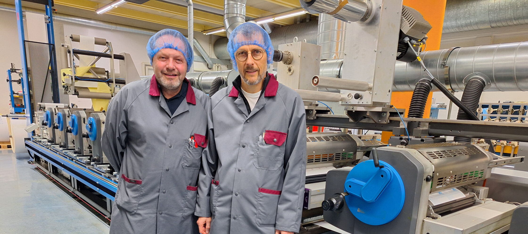 Salvador Hartmann, Produktionsleiter und Roger Wick, COO Etiketten & Flexible Verpackung, mit einer der drei modernisierten Druckmaschinen.